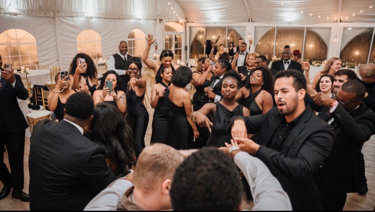 Wedding party dancing together in a tented Maryland reception with string lights