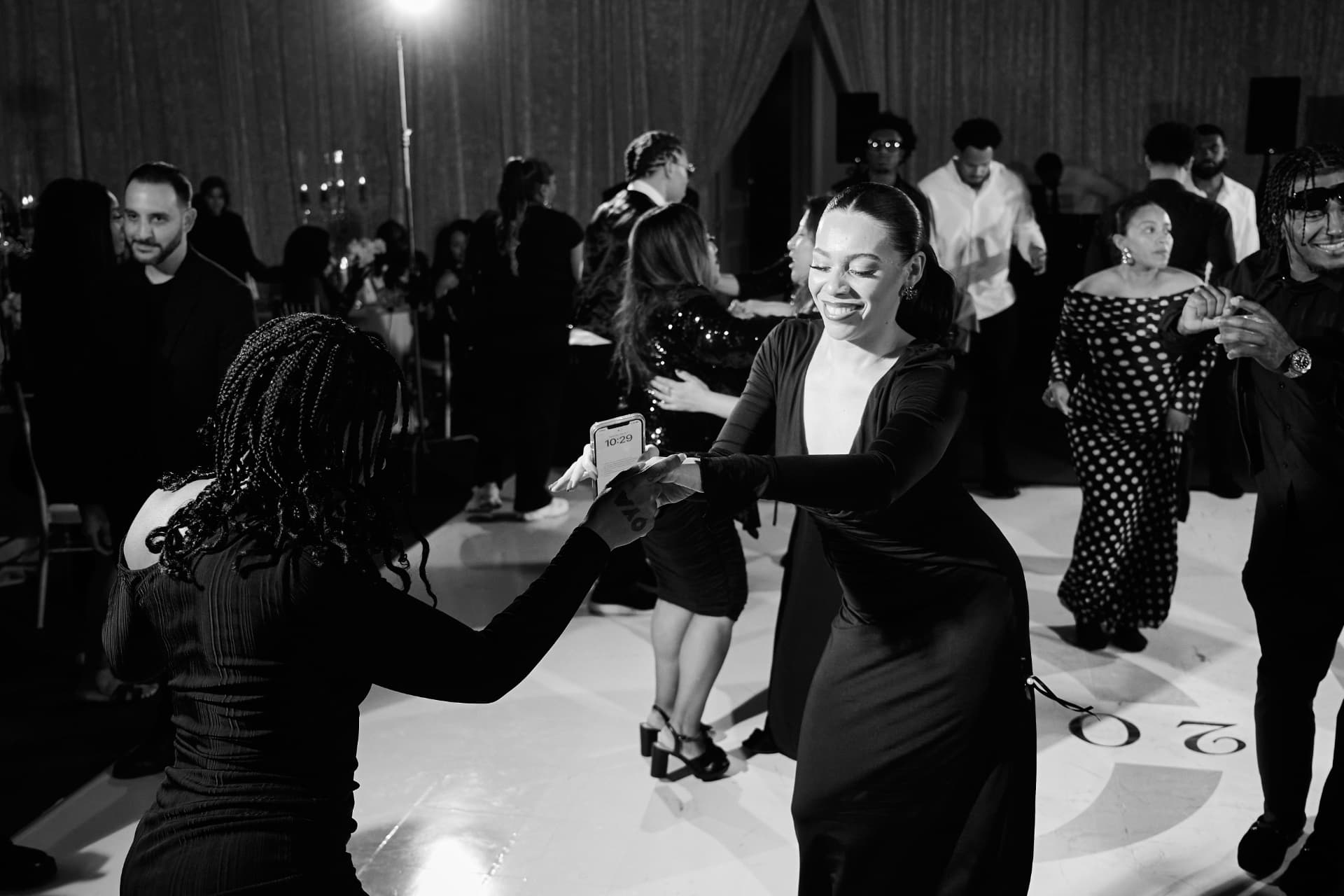 Black and white photo of guests dancing and laughing together at a formal wedding reception
