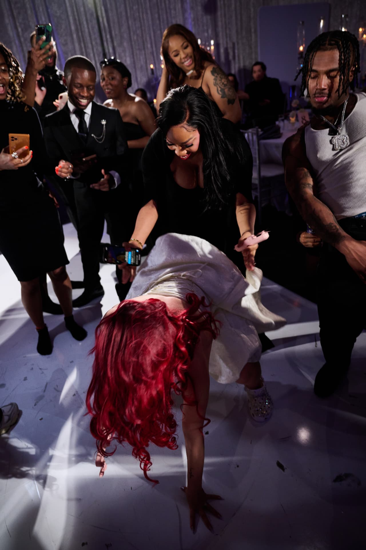 Guest dancing low on the white dance floor as the crowd cheers at a DC wedding reception